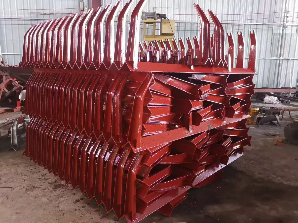 Red welded idler support frames stacked in a workshop