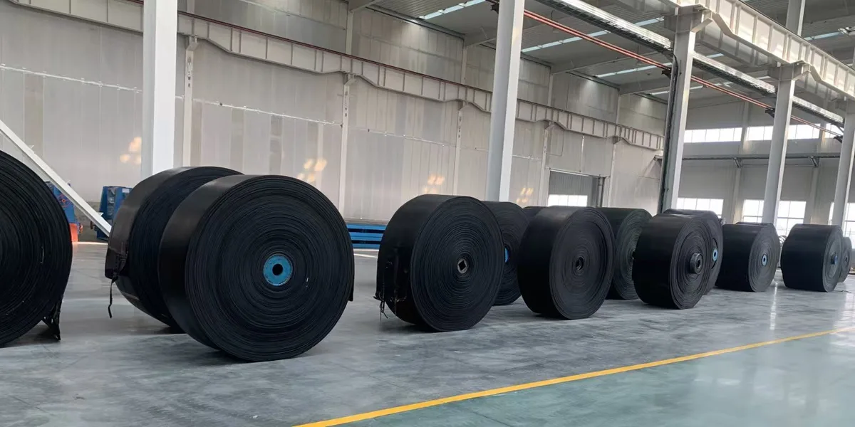 Large black conveyor belt rolls stored in a workshop